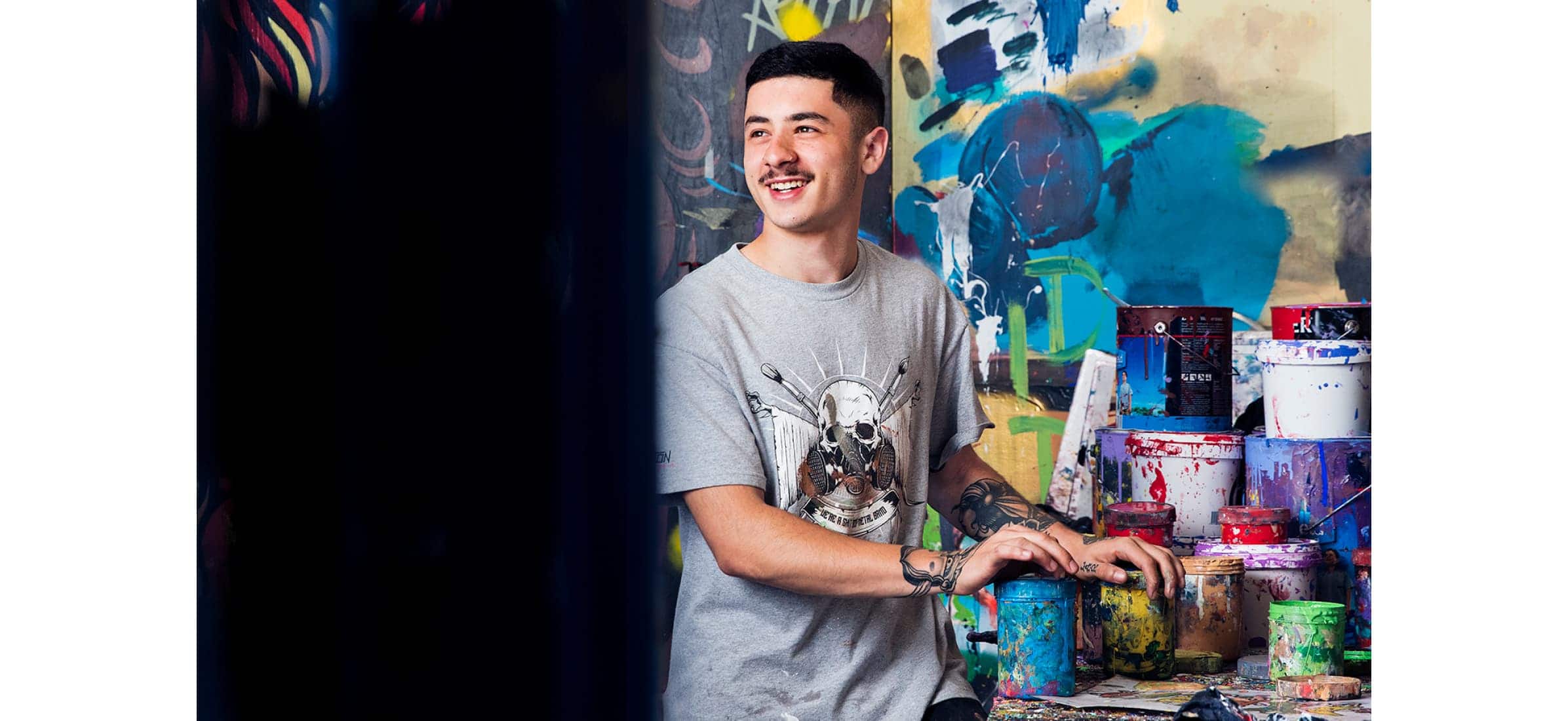 One of Apparition Media’s painters smiling with a collection of paint cans in the studio.
